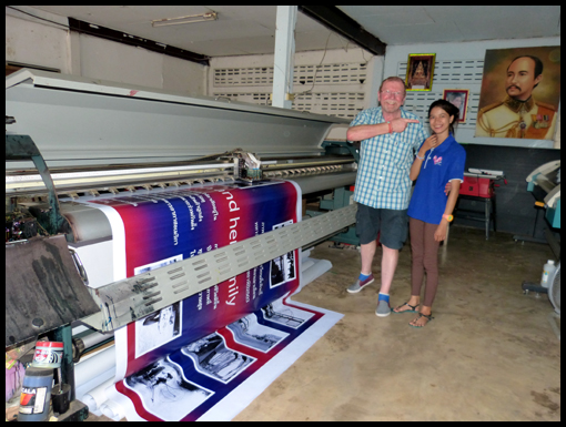 A young Thai student stands proudly by the banner she helped to make.