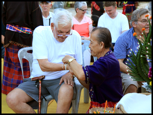 Alan Myers receiving a cotton wristband for good luck from a villager.