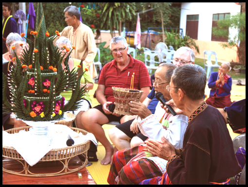 A village elder chants prayers with the group silent.