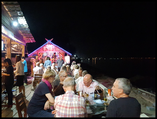 The group dine beside the Mekong and toast the trips success with the Anniversary mug.